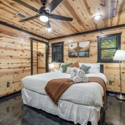 Second bedroom with a king bed, white linens, a brown throw, sage pillows and a floor lamp