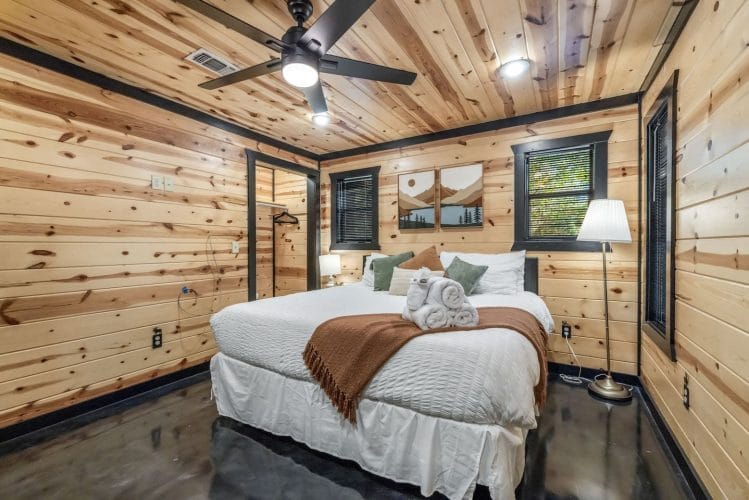 Second bedroom with a king bed, white linens, a brown throw, sage pillows and a floor lamp