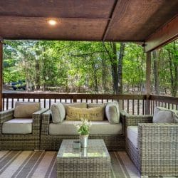 Outdoor sofa and chairs around a glass coffee table on the covered porch