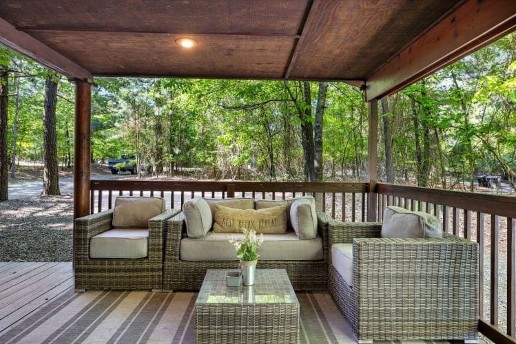 Outdoor sofa and chairs around a glass coffee table on the covered porch