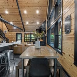 Long wood dining table next to the kitchen island and tall black-framed windows