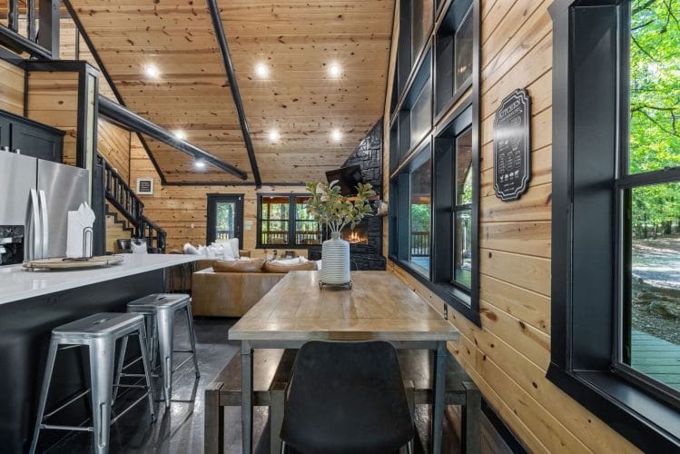 Long wood dining table next to the kitchen island and tall black-framed windows