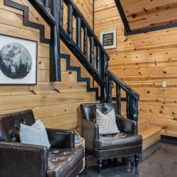 Staircase with a black railing beside two leather armchairs