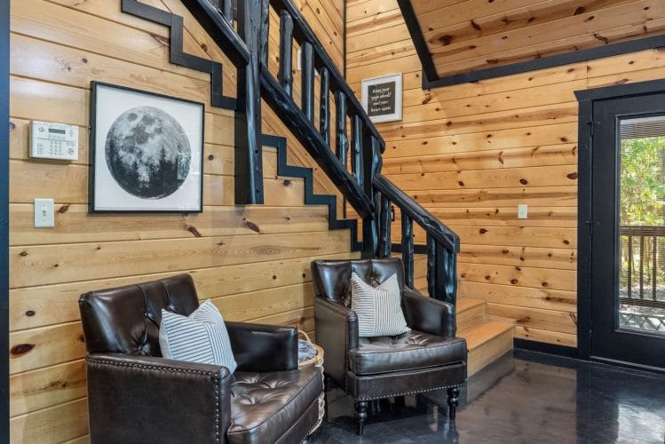 Staircase with a black railing beside two leather armchairs