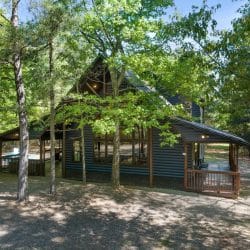 Side of the cabin with the roofline and porch among trees
