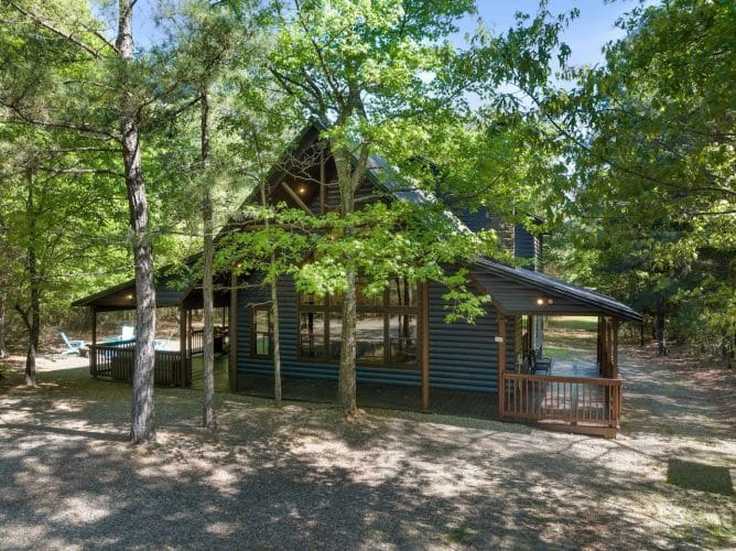 Side of the cabin with the roofline and porch among trees