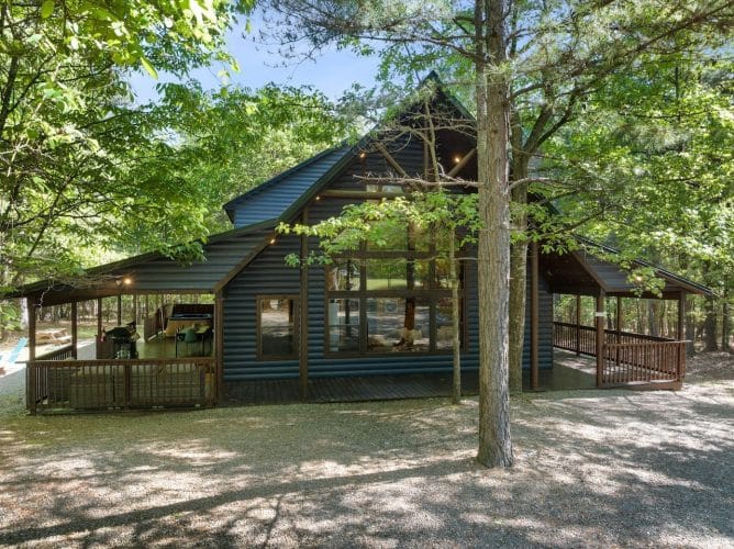 Wider view of the cabin and covered porch from the gravel drive