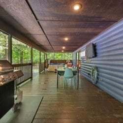 Gas grill on the covered porch with a long dining table and chairs beyond
