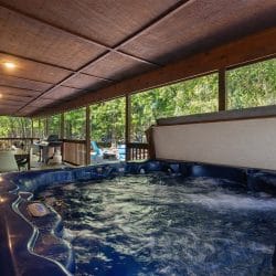 Hot tub on the covered porch with an outdoor dining table behind it
