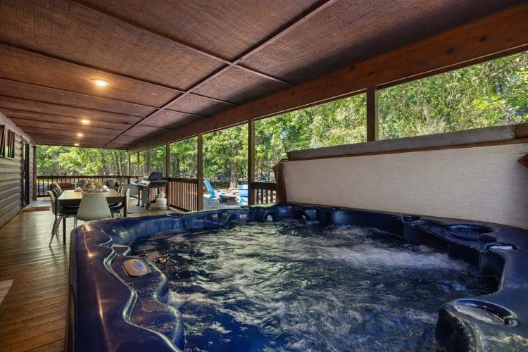 Hot tub on the covered porch with an outdoor dining table behind it