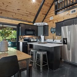 Kitchen with an island, stainless refrigerator and a wood dining table in front of the glass door