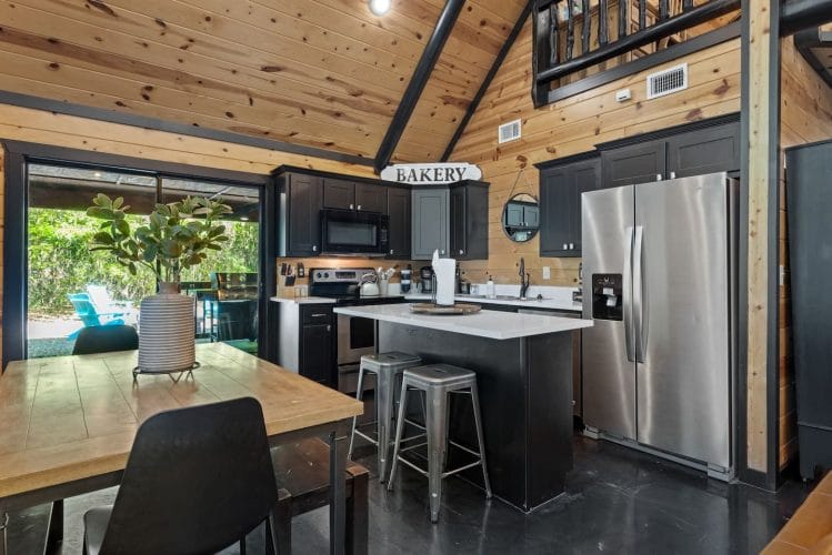 Kitchen with an island, stainless refrigerator and a wood dining table in front of the glass door