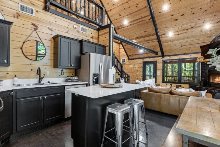 Island with metal stools and the living room beyond, under the loft railing