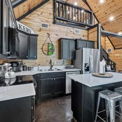 Kitchen counter with a knife block, a kettle and a stainless refrigerator under the loft railing