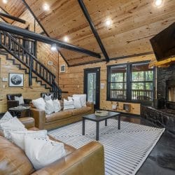 Living area with a gas fireplace in a dark stone surround, a TV above it and leather sofas