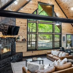 Vaulted pine ceiling with black beams, fireplace and TV, and leather sofas in the foreground