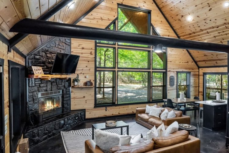 Vaulted pine ceiling with black beams, fireplace and TV, and leather sofas in the foreground