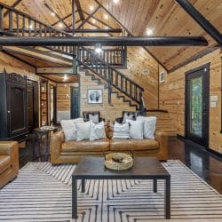 Leather sofas and a coffee table with the staircase and a black armoire behind