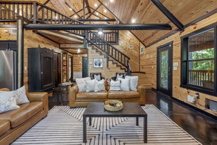 Leather sofas and a coffee table with the staircase and a black armoire behind