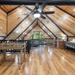 Loft from the far end with a foosball table, two beds and seating under black roof beams