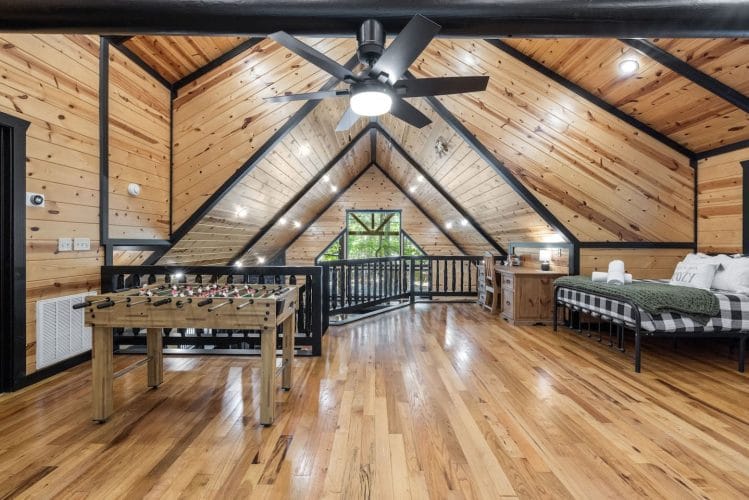 Loft from the far end with a foosball table, two beds and seating under black roof beams
