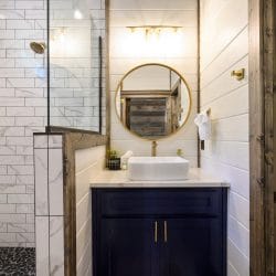 Bathroom sink with a gold faucet and round gold-framed mirror