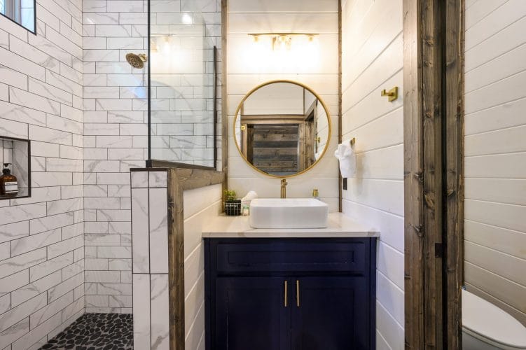 Bathroom sink with a gold faucet and round gold-framed mirror
