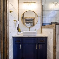 White vessel sink under a round gold mirror with a macrame hanging