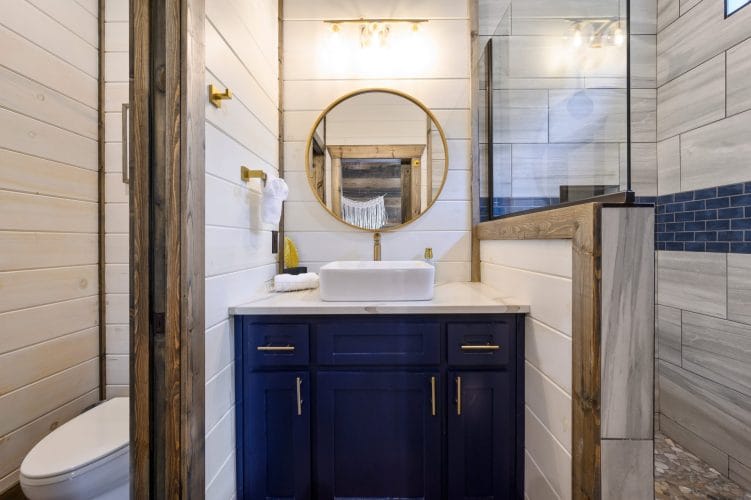 White vessel sink under a round gold mirror with a macrame hanging