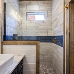Blue subway tile above a wood-framed tub edge