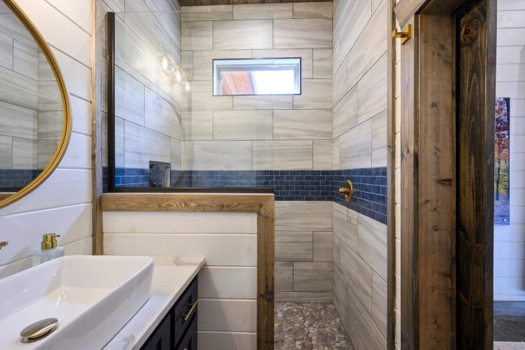 Blue subway tile above a wood-framed tub edge
