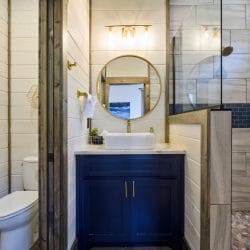Vessel sink with a gold faucet under a round mirror