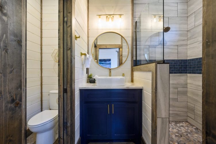 Vessel sink with a gold faucet under a round mirror