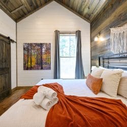 Gray curtains over a bedroom window with a forest photo on the wall