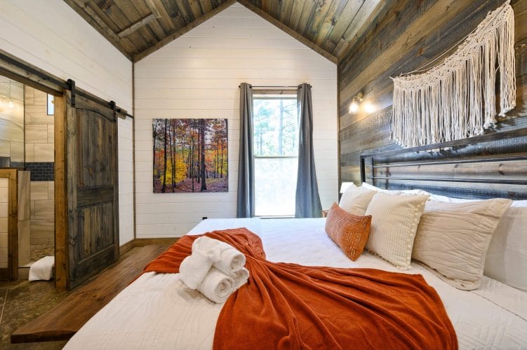 Gray curtains over a bedroom window with a forest photo on the wall