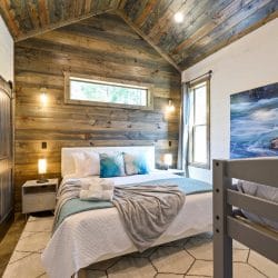Headboard with aqua pillows against a reclaimed wood wall