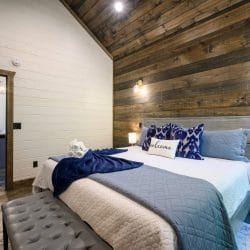 Bed headboard with a lamp and blue patterned pillows on a reclaimed wood wall