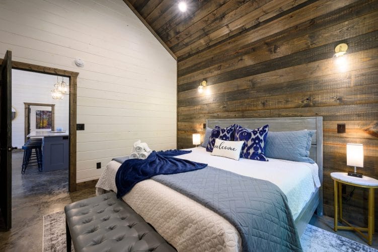 Bed headboard with a lamp and blue patterned pillows on a reclaimed wood wall