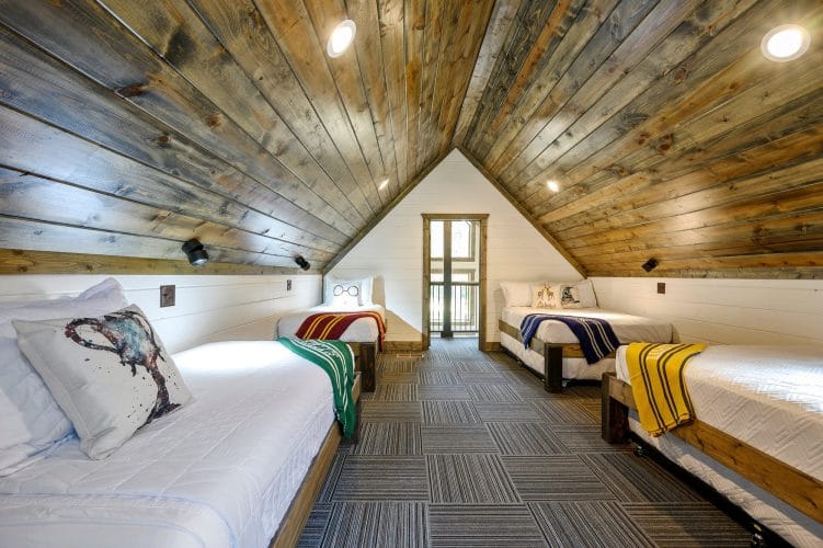 Upstairs room with beds under a vaulted wood ceiling and a balcony door