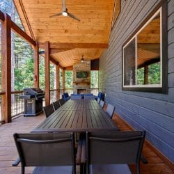 Covered porch with a stone fireplace, wall TV and blue outdoor sectional