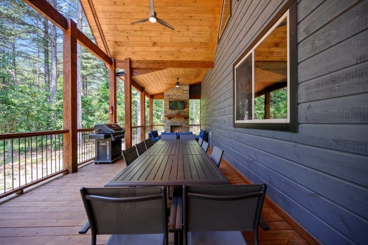Covered porch with a stone fireplace, wall TV and blue outdoor sectional