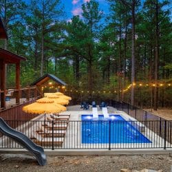Blue Adirondack chairs in a circle by the pool at dusk, with umbrellas and string lights