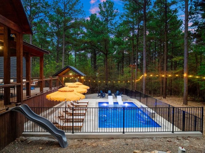 Blue Adirondack chairs in a circle by the pool at dusk, with umbrellas and string lights