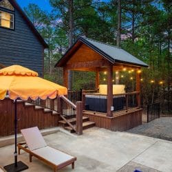 Covered hot tub under a timber pergola next to an orange umbrella