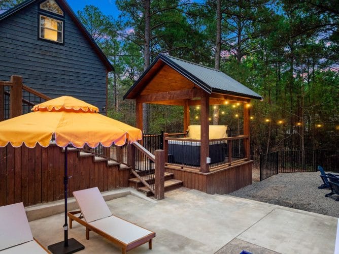 Covered hot tub under a timber pergola next to an orange umbrella
