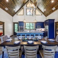 Blue kitchen island with white counters, a gold faucet and a wall oven under a window