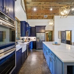 Navy cabinets, stainless refrigerator and a coffee maker on a white counter