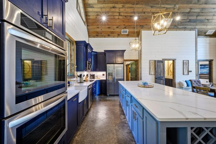 Navy cabinets, stainless refrigerator and a coffee maker on a white counter