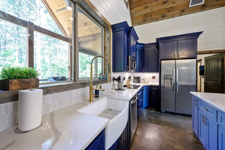 Gold faucet, an "Eat" sign, a utensil crock and a knife block against white tile