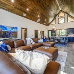 Brown leather sectional with blue and striped pillows and a wood door behind it